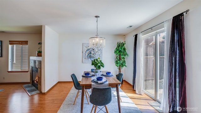 28843 213th Ct SE, Kent, WA 98042 - dining room featuring light wood finished floors, a chandelier, a fireplace with flush hearth, and baseboards