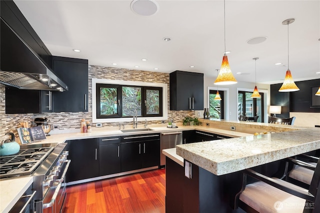 kitchen with dark cabinetry, stainless steel appliances, extractor fan, light countertops, and recessed lighting