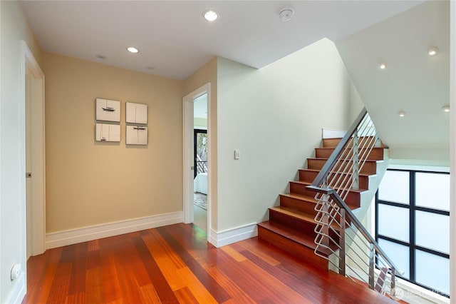 stairs featuring baseboards, wood finished floors, and recessed lighting
