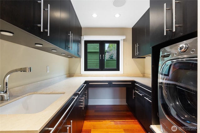 washroom featuring cabinet space, washer / dryer, light wood finished floors, and recessed lighting