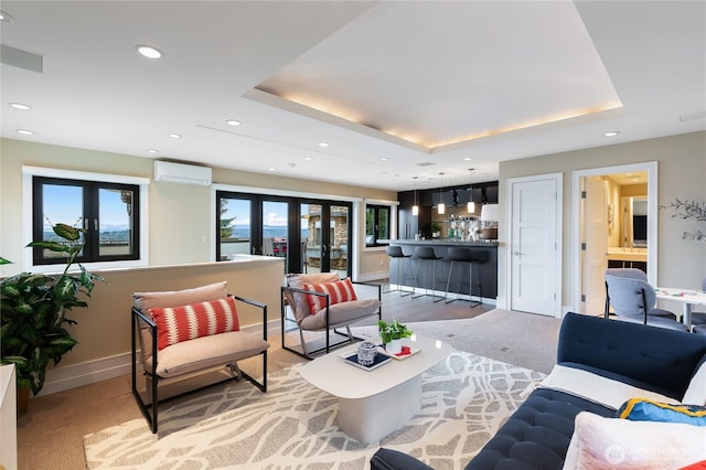 living area with a raised ceiling, recessed lighting, a wall mounted air conditioner, and baseboards