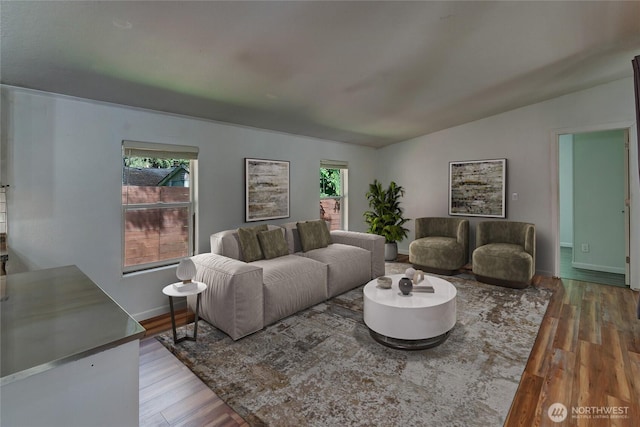 living area with plenty of natural light, wood finished floors, vaulted ceiling, and baseboards