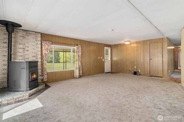 3180 Woodcock Rd, Sequim, WA 98382 - unfurnished living room with a wood stove, carpet, and wooden walls