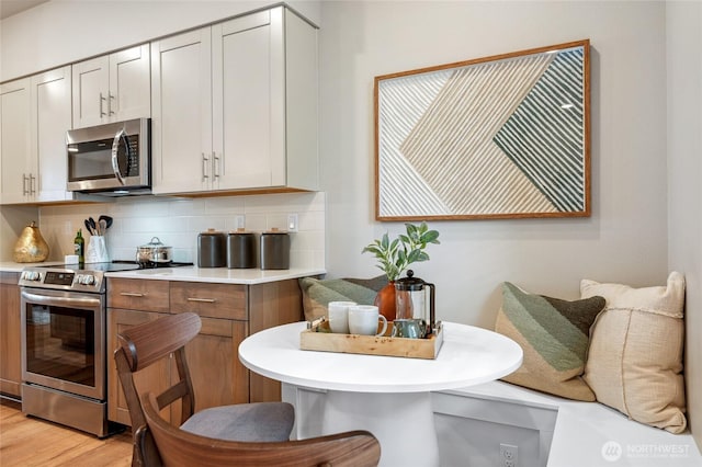 kitchen with stainless steel appliances, tasteful backsplash, light countertops, and light wood-style floors