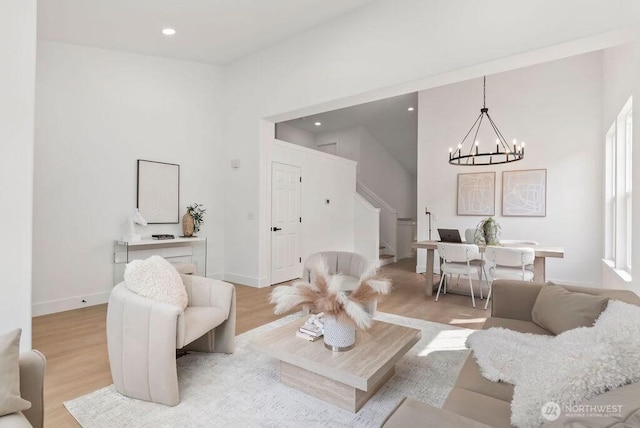 living area with stairs, a chandelier, light wood finished floors, recessed lighting, and baseboards