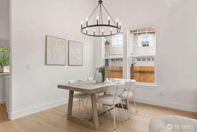 dining space with light wood-type flooring, a chandelier, and baseboards