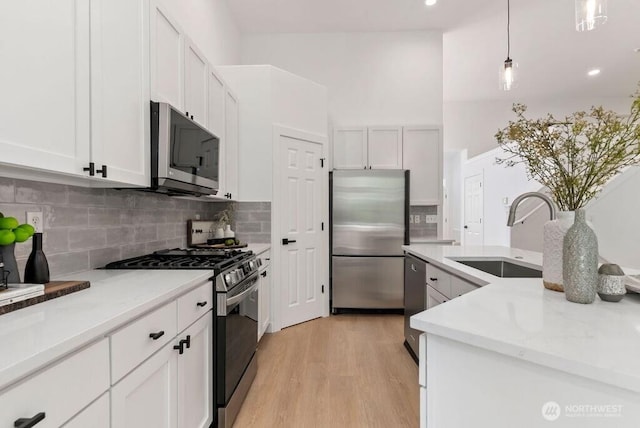 kitchen featuring stainless steel appliances, a sink, decorative backsplash, and white cabinets