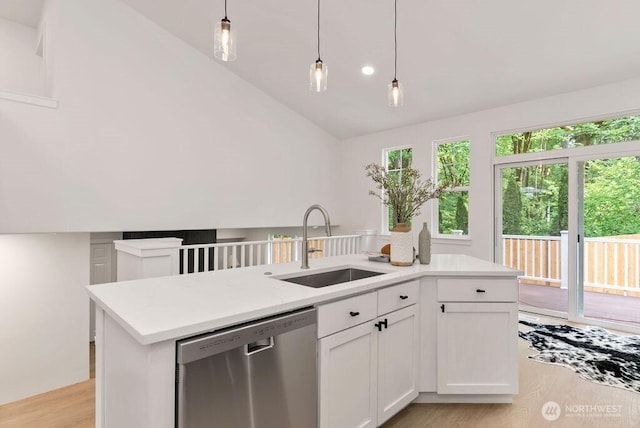 kitchen with dishwasher, a sink, light countertops, lofted ceiling, and light wood-style floors