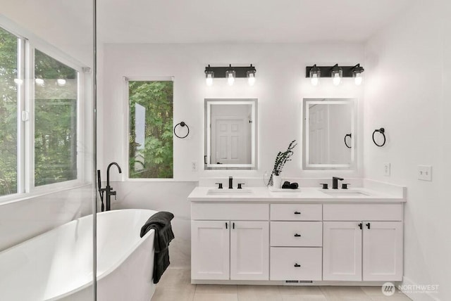 full bathroom featuring a freestanding tub, double vanity, and tile patterned floors