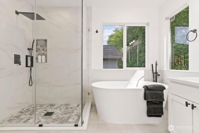 bathroom with a marble finish shower, a freestanding bath, vanity, and tile patterned floors