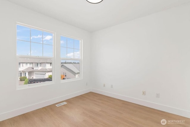 empty room featuring baseboards and light wood finished floors