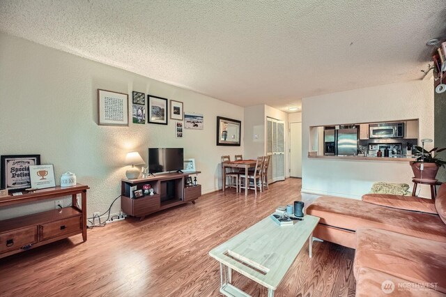living room featuring a textured ceiling, wood finished floors, and a textured wall