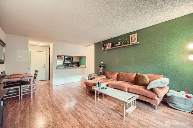 living room with a textured wall, a textured ceiling, and wood finished floors