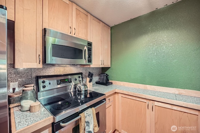 kitchen featuring stainless steel appliances, light brown cabinetry, tile countertops, a textured wall, and a textured ceiling
