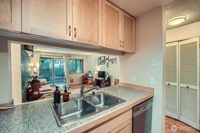 kitchen featuring dishwasher, a sink, light brown cabinetry, light countertops, and light wood-type flooring