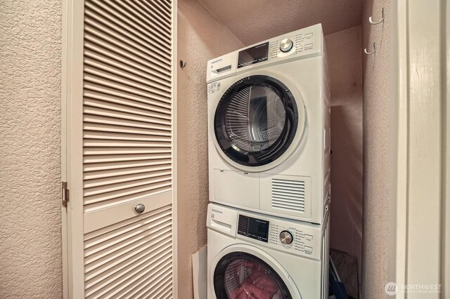 washroom featuring estacked washer and dryer and a textured wall