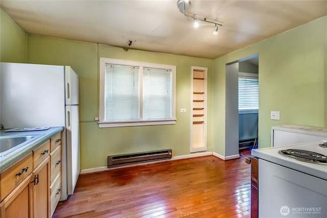 kitchen with a baseboard radiator, hardwood / wood-style floors, white appliances, track lighting, and baseboards