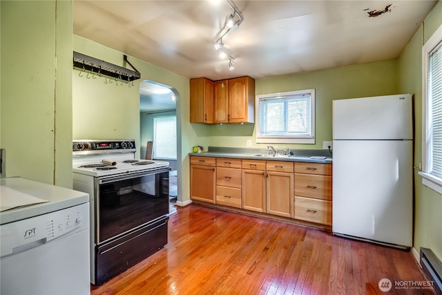 kitchen with white appliances, a sink, arched walkways, a baseboard heating unit, and track lighting