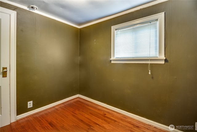 empty room featuring wood finished floors, ornamental molding, and baseboards