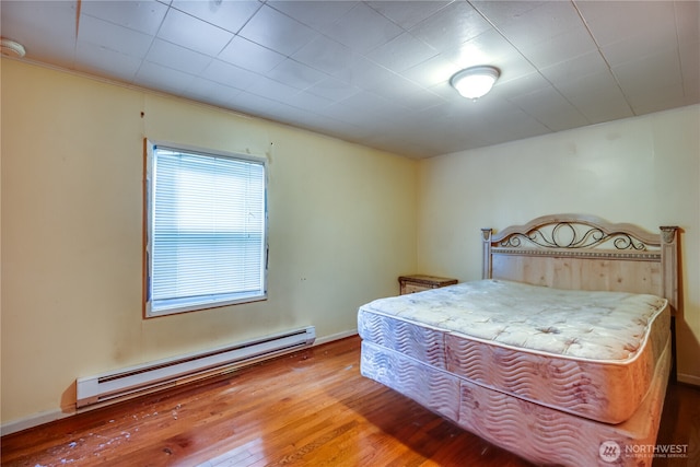 bedroom with a baseboard heating unit and hardwood / wood-style flooring