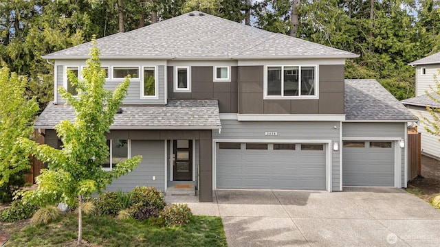 traditional home with roof with shingles, driveway, and an attached garage