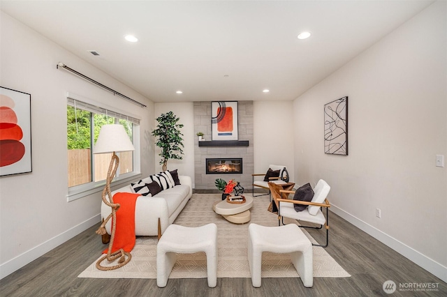 living area with wood finished floors, baseboards, recessed lighting, and a tiled fireplace