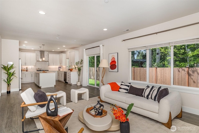 living area featuring healthy amount of natural light, recessed lighting, dark wood-style floors, and baseboards