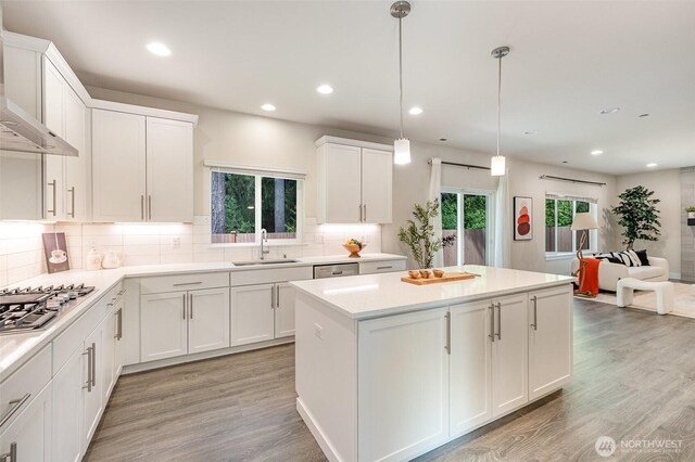 kitchen featuring a sink, appliances with stainless steel finishes, wall chimney range hood, healthy amount of natural light, and recessed lighting