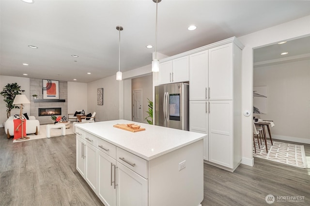 kitchen featuring smart refrigerator, light wood-type flooring, a center island, white cabinets, and a fireplace