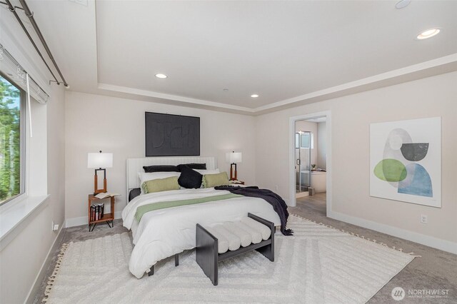 bedroom featuring baseboards, a tray ceiling, recessed lighting, ensuite bath, and light colored carpet