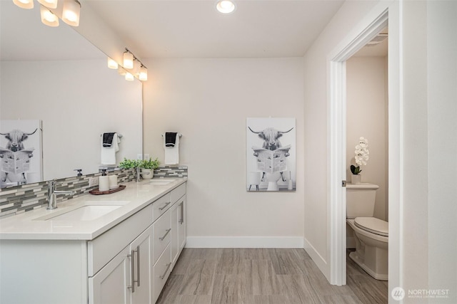 full bath with baseboards, double vanity, toilet, backsplash, and recessed lighting