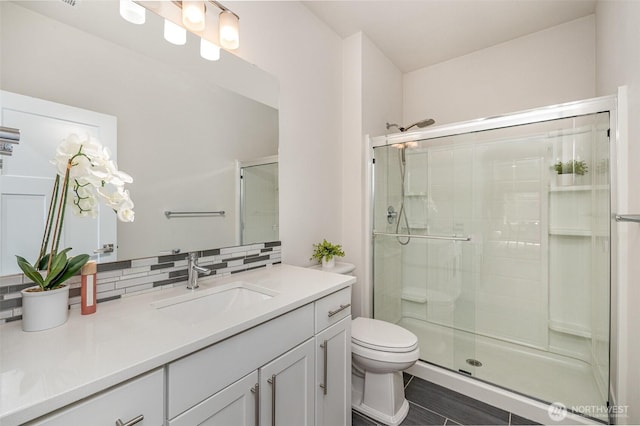 bathroom featuring a stall shower, tasteful backsplash, toilet, and vanity