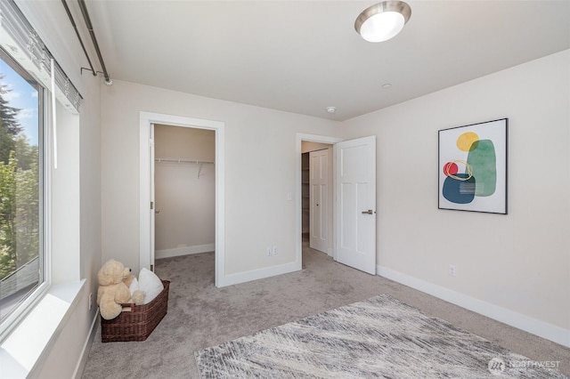 carpeted bedroom featuring baseboards and a spacious closet