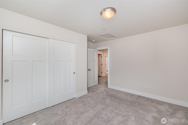 unfurnished bedroom featuring carpet floors, baseboards, a closet, and attic access