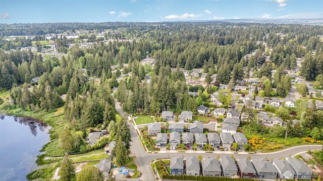aerial overview of property's location with nearby suburban area, a large body of water, and a heavily wooded area