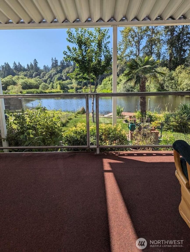 view of patio / terrace with a water view and view of wooded area
