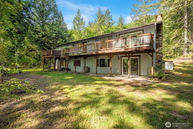 rear view of house featuring a lawn, a deck, a chimney, and a patio