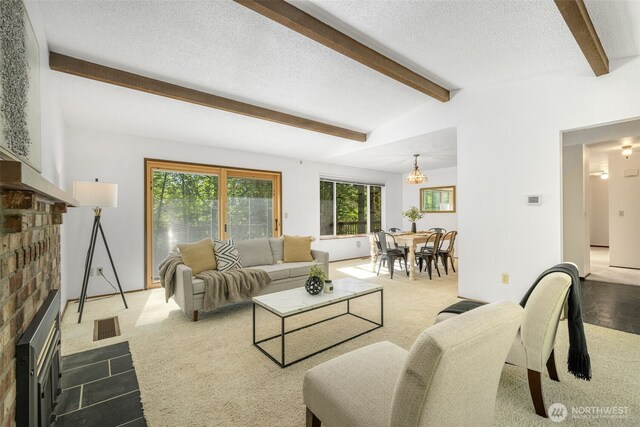 living room with a fireplace, a textured ceiling, dark colored carpet, and a chandelier