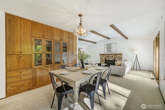 dining area with light carpet, a fireplace, and a chandelier