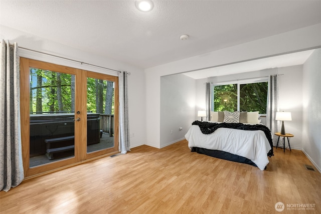bedroom with access to outside, light wood-style flooring, french doors, and baseboards