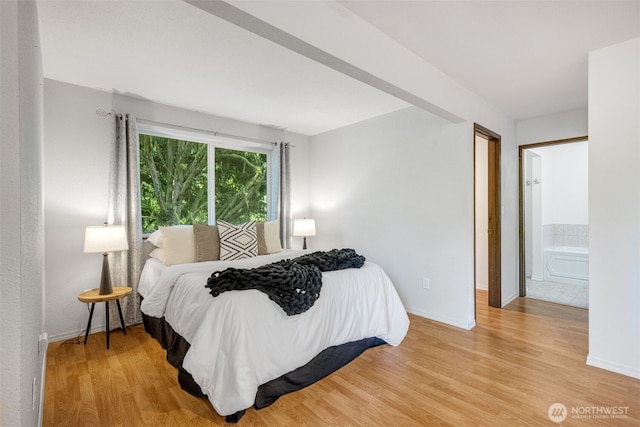 bedroom featuring light wood-type flooring, baseboards, and connected bathroom