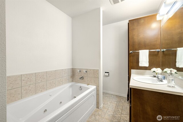 bathroom featuring vanity, a jetted tub, and baseboards
