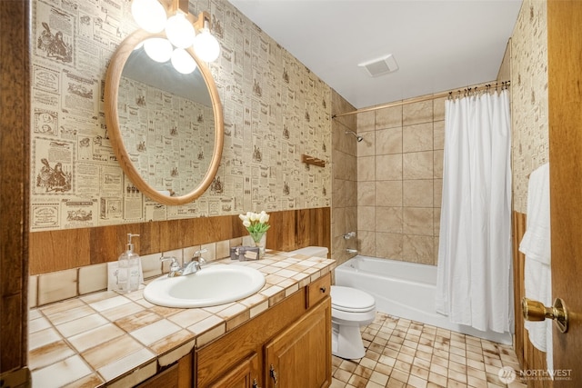full bath with wallpapered walls, shower / bath combination with curtain, toilet, and vanity