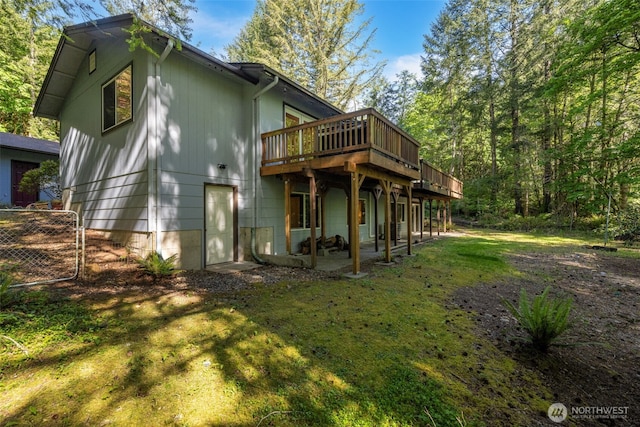 back of house with a deck, a patio area, and a lawn