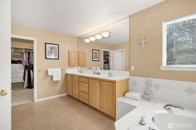 9437 NE Coral Ct, Bainbridge Island, WA 98110 - bathroom with double vanity, a garden tub, a spacious closet, and baseboards