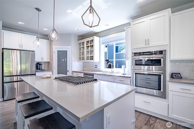 4213 Caddyshack Dr NE, Lacey, WA 98516 - kitchen featuring stainless steel appliances, a sink, a center island, glass insert cabinets, and backsplash
