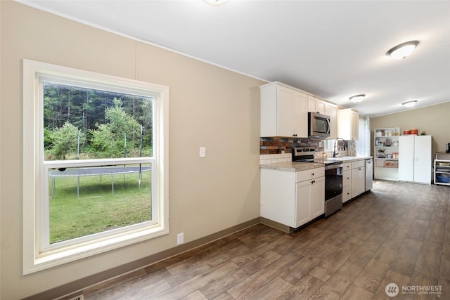 486 Justus Rd, Cinebar, WA 98533 - kitchen with appliances with stainless steel finishes, dark wood-style flooring, decorative backsplash, white cabinetry, and a sink