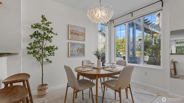 dining area featuring baseboards, a chandelier, and light colored carpet