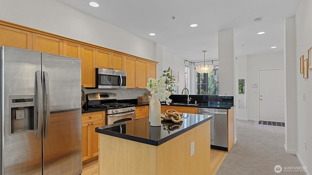 kitchen with stainless steel appliances, a sink, dark countertops, recessed lighting, and a kitchen island