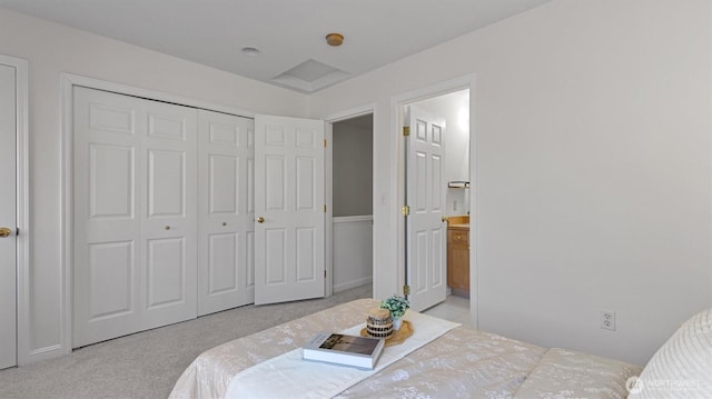 bedroom with light colored carpet, a closet, and ensuite bath